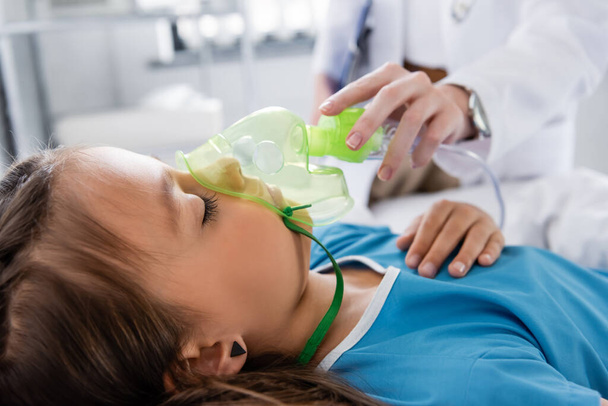 Pediatra desfocado segurando máscara de oxigênio perto de criança doente no hospital  - Foto, Imagem