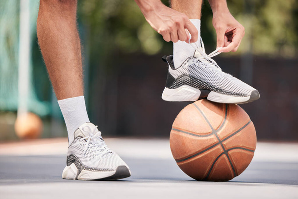 Tie shoes, sports and hands on a basketball court getting ready for training, cardio workout and fitness exercise. Footwear, sneakers and healthy athlete in preparation for a practice game or match. - 写真・画像