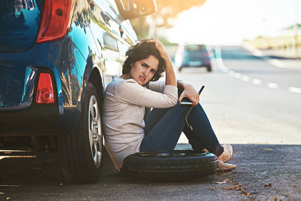 Wo ein Mechaniker ist, wenn man ihn braucht. Eine junge Frau sitzt neben ihrem kaputten Auto am Straßenrand - Foto, Bild