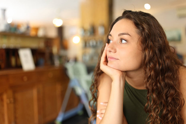 Distracted and pensive woman looking away in a restaurant - Photo, image