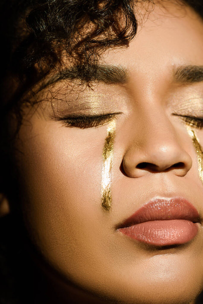 close up of african american woman with golden tears on cheeks and closed eyes - Valokuva, kuva