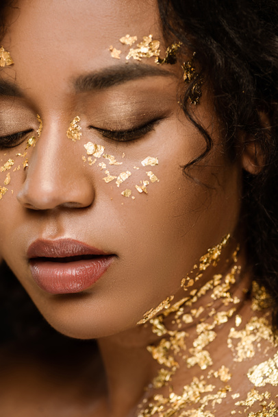 close up of curly african american woman with golden paint on face and neck - Foto, Imagen