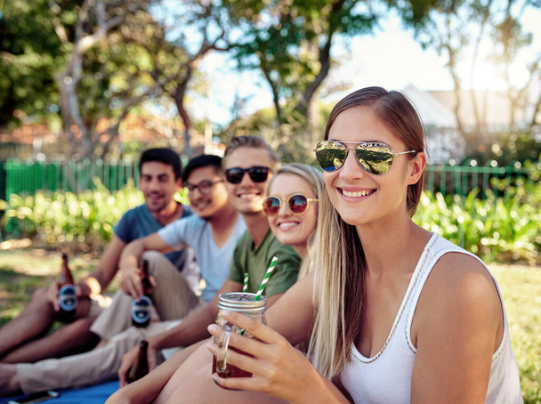 Esto es lo mejor. Retrato recortado de una joven atractiva disfrutando de unas copas con amigos afuera bajo el sol de verano - Foto, imagen