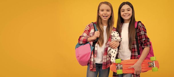 Liseli kızlar. Sıradan tişörtlü mutlu çocuklar sırt çantalı oyuncak ve bozuk para taşıyorlar, sıradan bir yaşam tarzı. Öğrenci portresi, stüdyo afişi. Okul çocuğu yüzü - Fotoğraf, Görsel