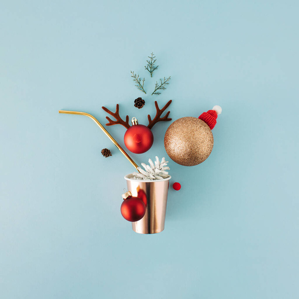 Conceito de saudação de Natal com vidro de bebida de papel, palha e ornamentos em fundo azul. - Foto, Imagem