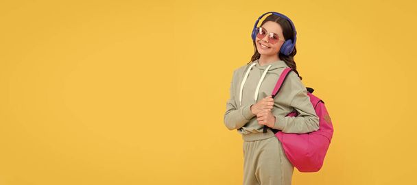 happy child in earphones carry backpack. back to school. knowledge and education. Casual teen child horizontal poster. Banner header, copy space - Photo, image