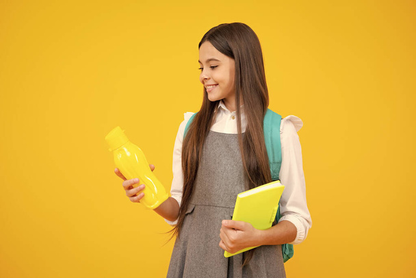 Gelukkige schoolmeisje met boeken drinken waterfles op schooldag. Terug naar school, lifestyle concept - Foto, afbeelding