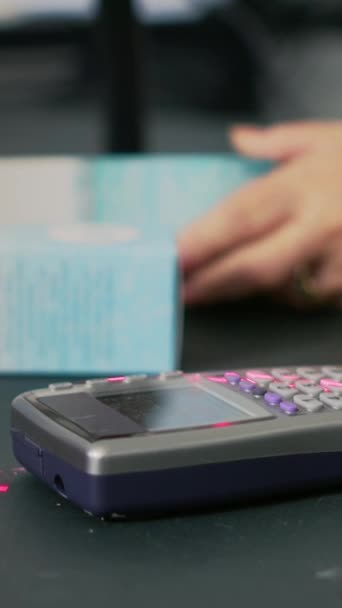 Dikey video: Müşteriler eczacılık ürünlerini çok akıllı bir şekilde satın alıyorlar, NFC ödemelerini tezgahın üzerinde yapıyorlar. Eczanede ilaçlara hiç para ödemeyen bir kadın. Kapatın. El kamerasıyla.. - Video, Çekim