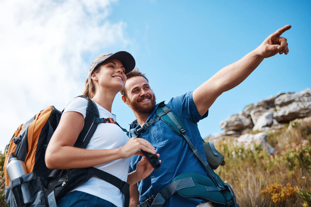 Couple, pointing and bonding on hiking mountains, nature earth environment or countryside hills in Canada. Smile, happy and hiker man and woman backpacking or sightseeing camping land with binoculars. - Photo, Image