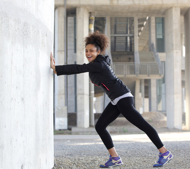 Χαμογελαστός νεαρός σπορ γυναίκα που εκτείνεται άσκηση σε εξωτερικούς χώρους - Φωτογραφία, εικόνα