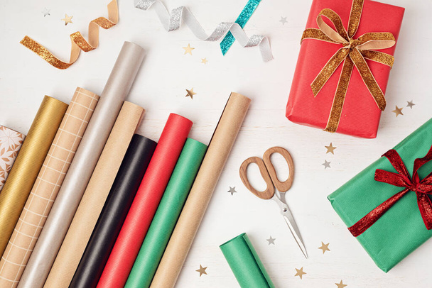 Karácsonyi háttér ajándékdobozok és tekercsek színes kraft csomagolópapír. Karácsonyi ünnepség, felkészülés a téli ünnepekre. Ünnepi mockup, felülnézet, lapos fekvés - Fotó, kép