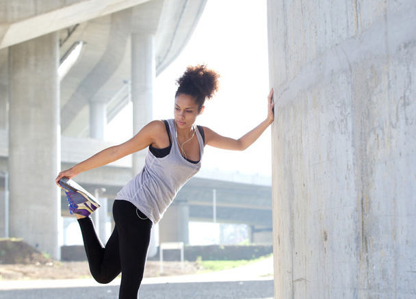 Молодая женщина растягивает мышцы ног на открытом воздухе
 - Фото, изображение
