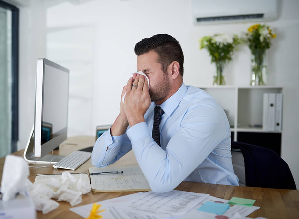 His sinuses are flaring up again. a young businessman suffering with allergies at work - Foto, imagen