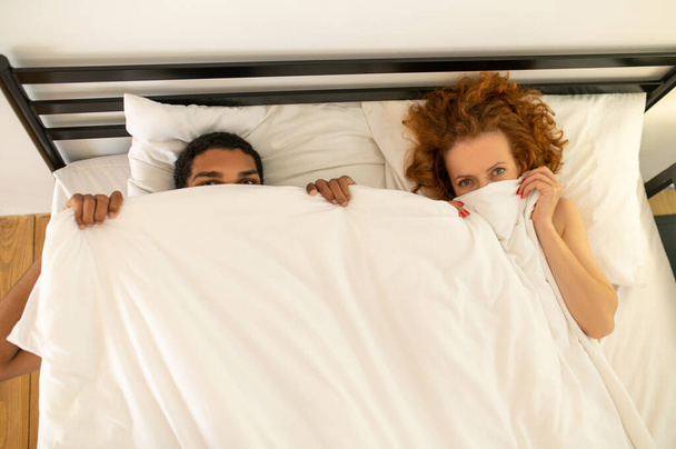 Aufwachen. Junges Paar morgens unter der Decke im Bett - Foto, Bild
