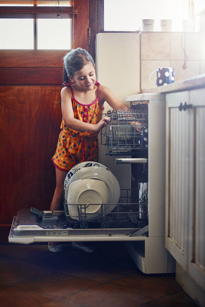 Loading the dishwasher. a little girl using a dishwashing machine at home - 写真・画像