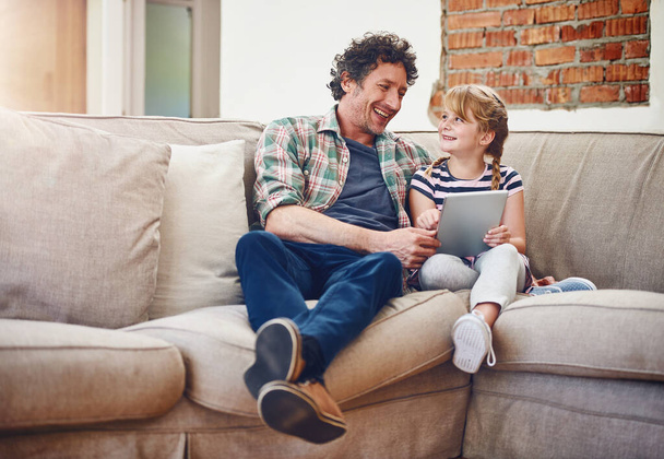 Guardiamo il nostro film preferito. un padre e la sua figlioletta utilizzando un tablet digitale a casa - Foto, immagini