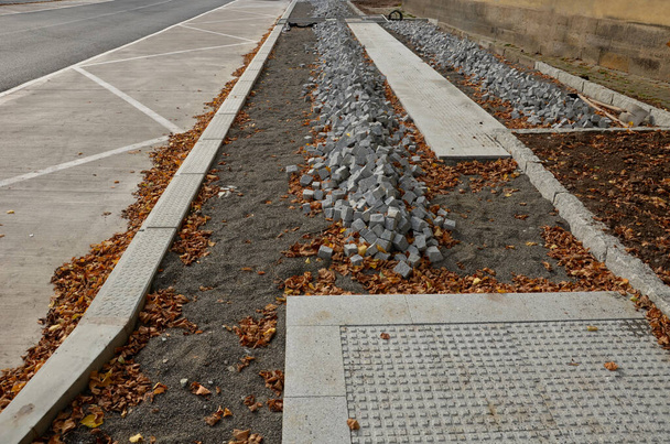 pavers made of stone cubes who can create beautiful mosaics. piles prepared in fine gravel for laying between curbs. the mayor ordered new sidewalks from the construction company - Photo, Image