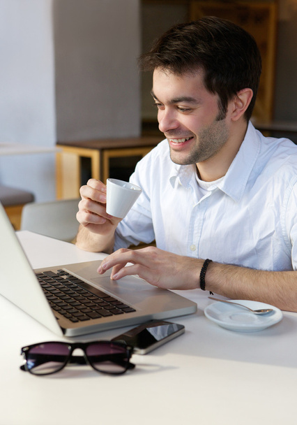 Молодой человек работает из дома на ноутбуке - Фото, изображение