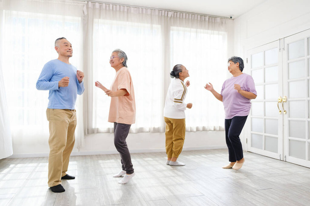 Активная азиатская старшая группа смешивается с мужскими и женскими упражнениями, танцуя вместе дома с расслаблением, улыбкой и смехом. Активность в помещении для пожилых людей и пенсионеров. - Фото, изображение