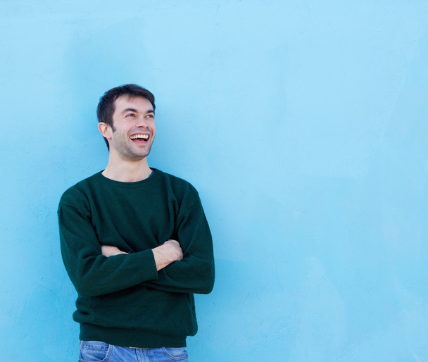 Onnellinen nuori mies nauraa sinistä taustaa vasten
 - Valokuva, kuva