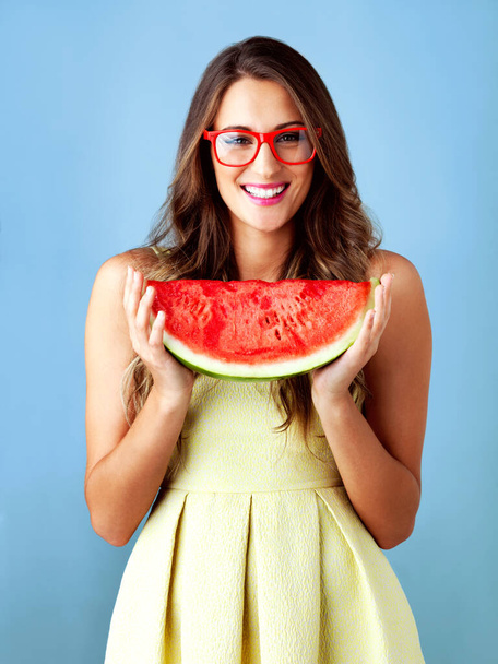 Самый летний фрукт в мире. Студийный снимок привлекательной молодой женщины, позирующей на синем фоне - Фото, изображение