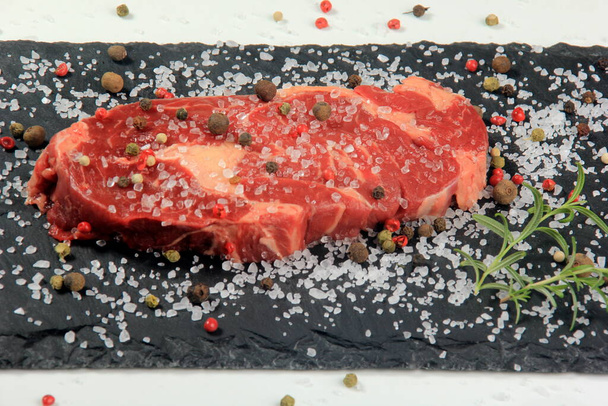 Filete fresco de costilla cruda en plato de piedra negra con sal, Filete crudo con especias - Foto, Imagen