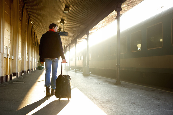 Mladý muž s taškou na vlakovém nádraží - Fotografie, Obrázek