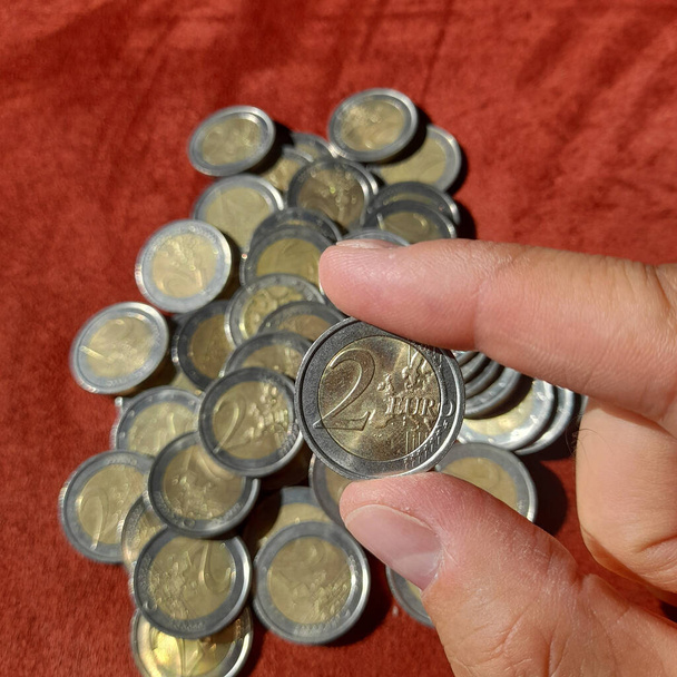 Moneda de 2 euros en manos de un hombre - Foto, Imagen
