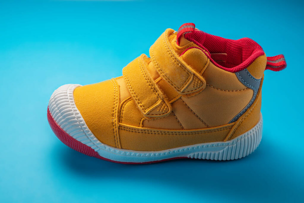 Zapatos de bebé amarillos. Zapatillas deportivas para niños aisladas sobre fondo azul - Foto, Imagen