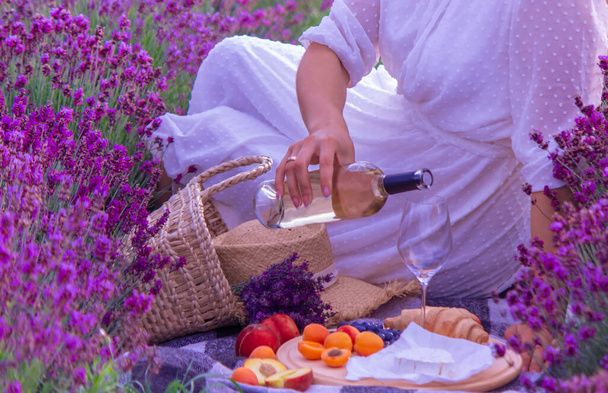 Nuori nainen kaataa viiniä lasiin laventelipellolla. valikoiva kohdentaminen - Valokuva, kuva