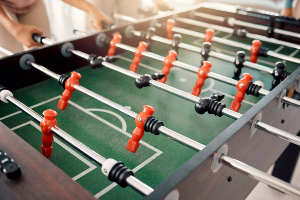 Foosball, game and fun with people playing a game inside of a clubhouse or at a party together. Soccer, table and competition with friends bonding over a match of football together for recreation. - Фото, изображение
