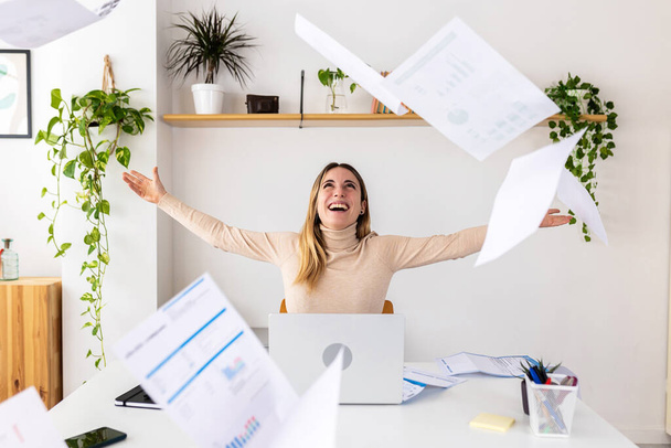 Молода збуджена весела жінка-підприємець кидає папери, святкуючи успіх бізнесу в офісі
 - Фото, зображення