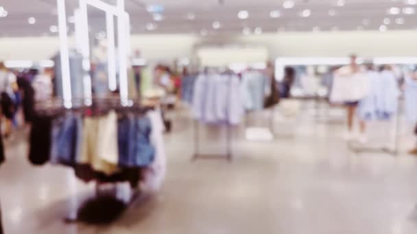 Moda, comercio minorista y tienda, visión interior borrosa de la tienda de ropa de ropa en el centro comercial de lujo como fondo desenfocado. Imágenes de alta calidad 4k - Metraje, vídeo