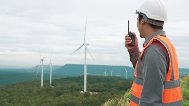 Ingenieur werkzaam op een windmolenpark op de top van een heuvel of berg op het platteland. Progressief ideaal voor de toekomstige productie van hernieuwbare, duurzame energie. Energieopwekking uit windturbine. - Video