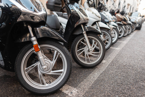 Motorfietsen staan geparkeerd in de stad. Fietswielen met rubber. Stedelijk vervoer in een Europese stad, Italië  - Foto, afbeelding