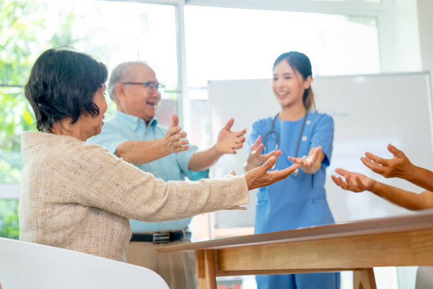 Back of senior woman look at pretty nurse or doctor woman show example and explain good practice to exercise or stretching in elderly healthcare clinic. - Photo, Image