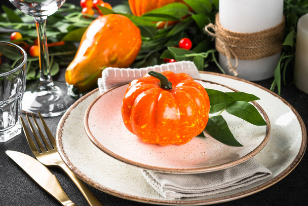 Table setting with plate, pumpkin and candles at wooden table. Autumn table decorations. Thanksgiving food, dinner concept. - 写真・画像