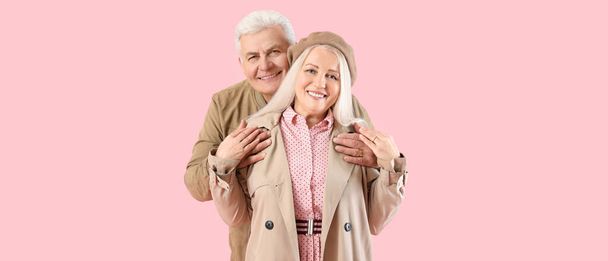 Portrait of happy elderly couple on pink background - Foto, afbeelding