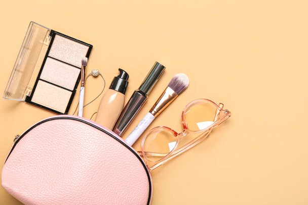 Bolsa rosa con cosméticos y accesorios sobre fondo beige - Foto, imagen
