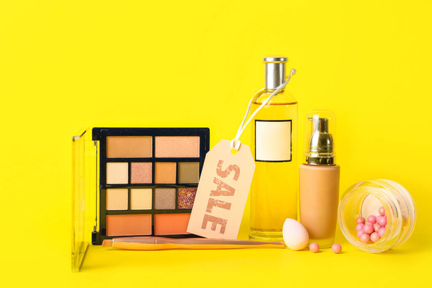 Produtos cosméticos e acessórios com etiqueta de venda em fundo amarelo - Foto, Imagem