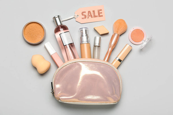 Borsa con prodotti cosmetici e targhetta vendita su fondo grigio - Foto, immagini