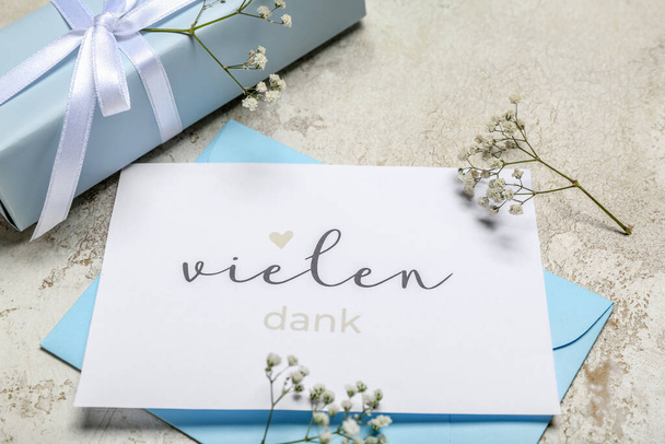 Card with text VIELEN DANK, envelope, flowers and gift box on grunge background - Foto, imagen
