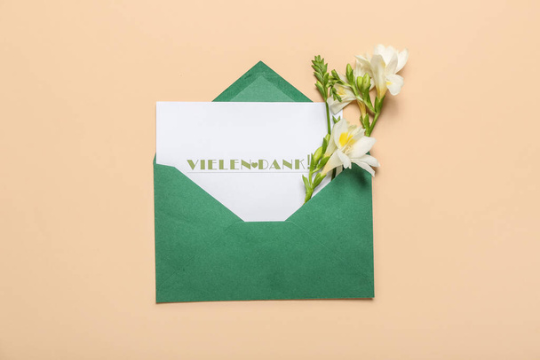 Tarjeta con texto VIELEN DANK y flores de freesia sobre fondo de color - Foto, Imagen