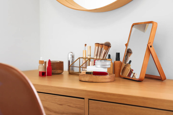 Διαφορετικά καλλυντικά προϊόντα και αξεσουάρ μακιγιάζ στο τραπέζι στο δωμάτιο - Φωτογραφία, εικόνα