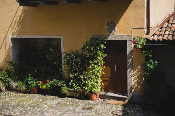 Krásný exteriér jednoho z domů v Morcote s malou květinovou zahradou u vchodu, kanton Ticino, Švýcarsko. - Fotografie, Obrázek