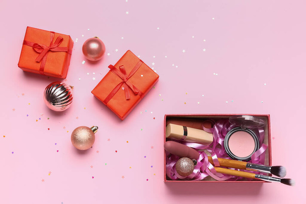 Gift boxes with makeup products and Christmas balls on pink background - Fotoğraf, Görsel