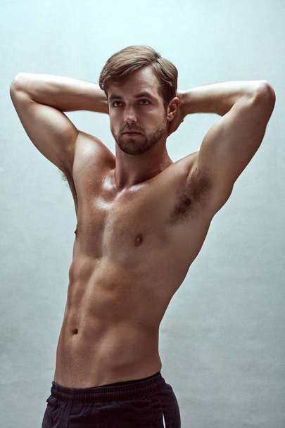 Siinä on jotain katsottavaa. komea paljain rinnoin varustettu nuori mies poseeraa studiossa - Valokuva, kuva