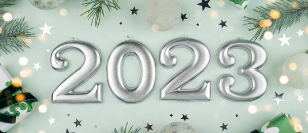 Числа 2023 года, сделанные при свечах. Елка, подарочная коробка, праздничное оформление на светло-зеленом фоне. Рождественская открытка. Концепция карты "С Новым 2023 годом". Плоский, вид сверху - Фото, изображение