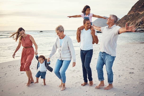 Szczęśliwa duża rodzina, wakacje i spacer po plaży dla jakości spędzania czasu w plenerze. Matka, ojciec i dziadkowie z dziećmi bawią się z uśmiechem na rodzinnej wycieczce nad ocean. - Zdjęcie, obraz