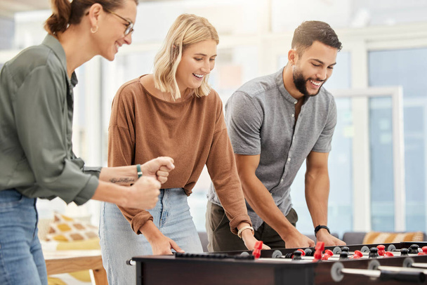 Business people play foosball table in office for team building competition, staff motivation or happiness in startup. Employees enjoy creative football games for happy teamwork challenge in company. - 写真・画像
